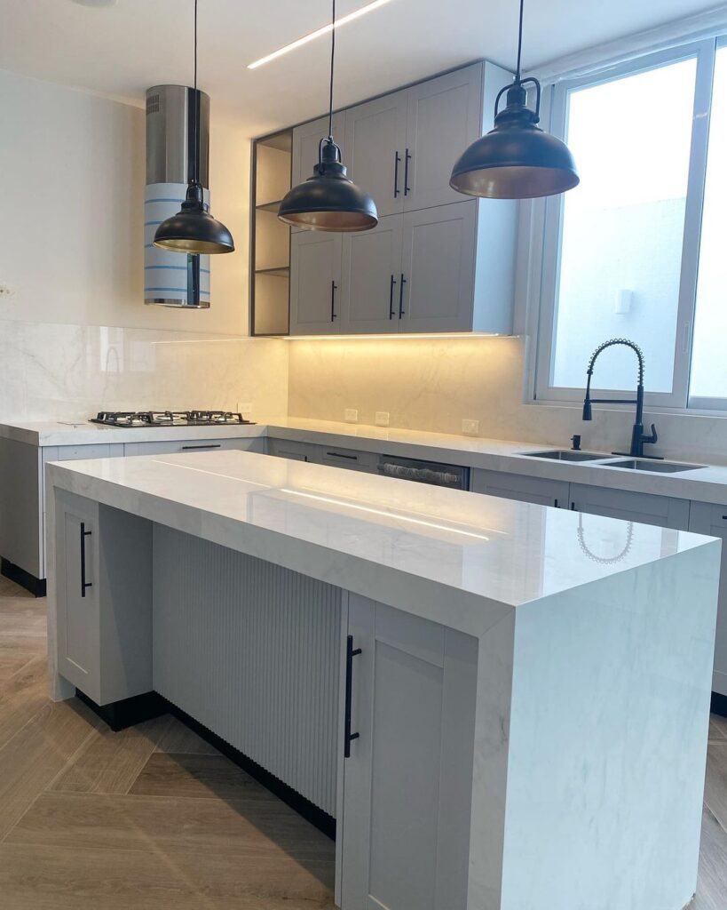 Modern white kitchen with black pendant lights and stainless accents