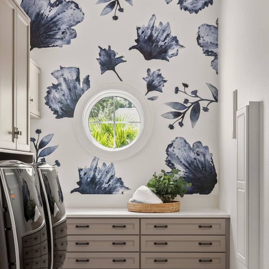 Laundry room with large blue floral wallpaper and round window.