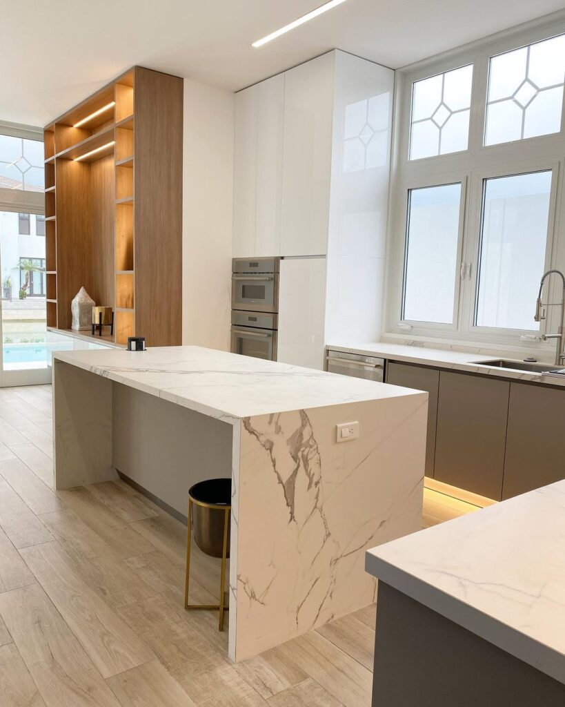 Modern kitchen with marble island and wood shelving.