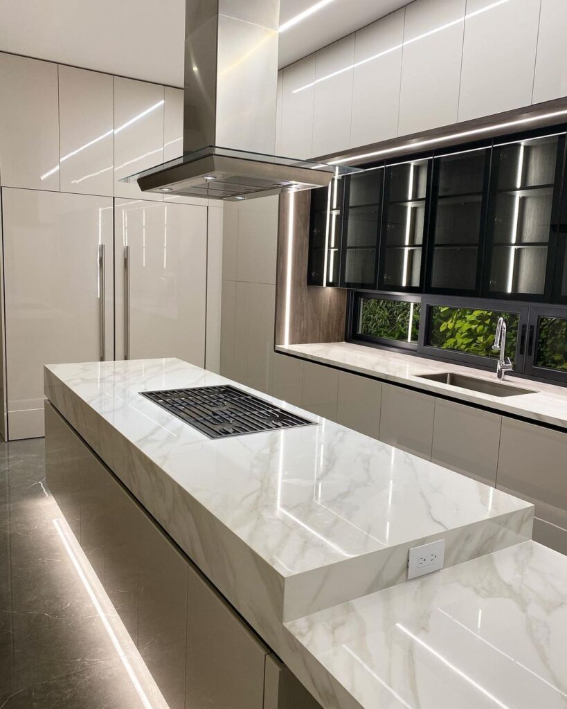 Modern white kitchen with marble island and LED lighting.