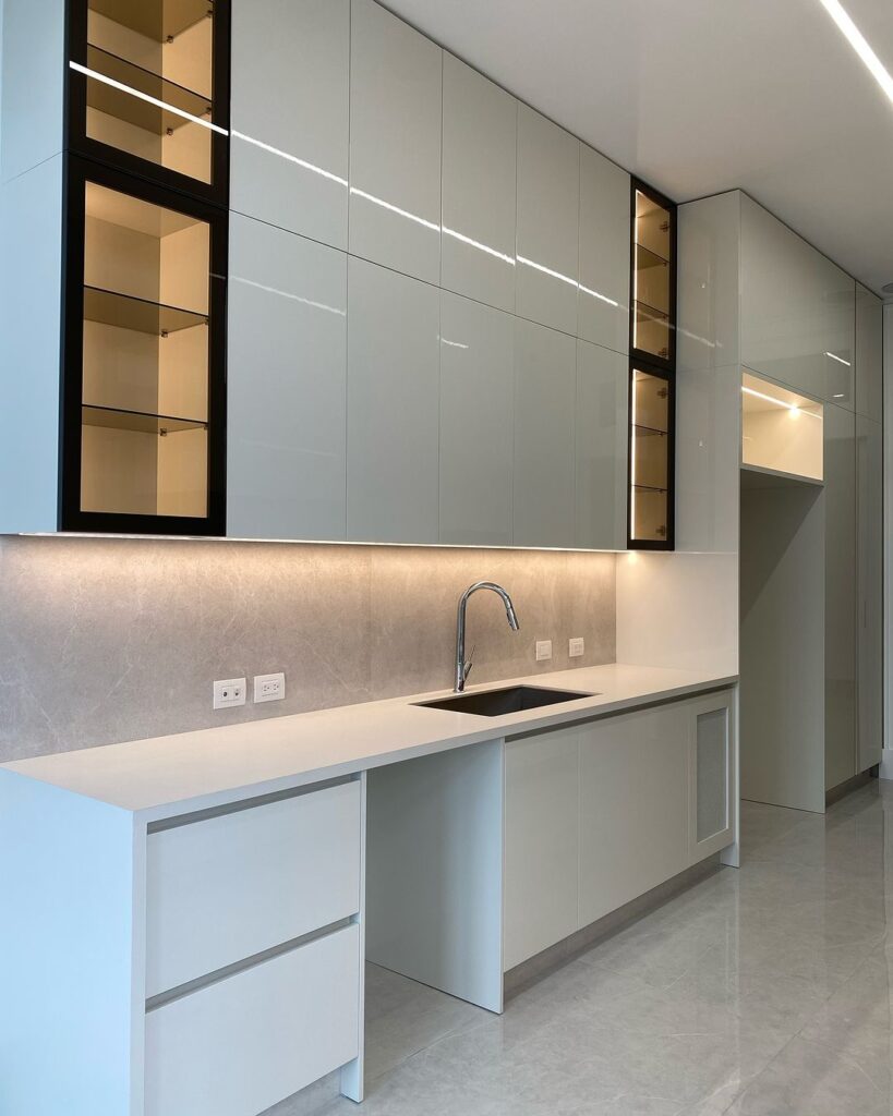 Modern white kitchen featuring vertical glass cabinets and LED lighting