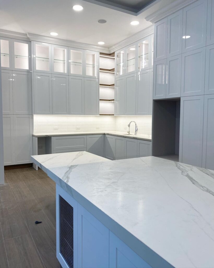 All-white kitchen with glass-front cabinets and marble island