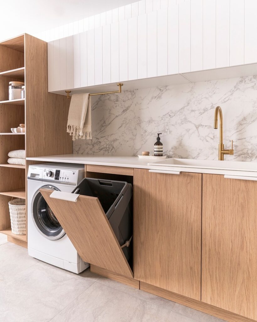 Minimalist laundry room with wooden cabinets marble backsplash and concealed washer.