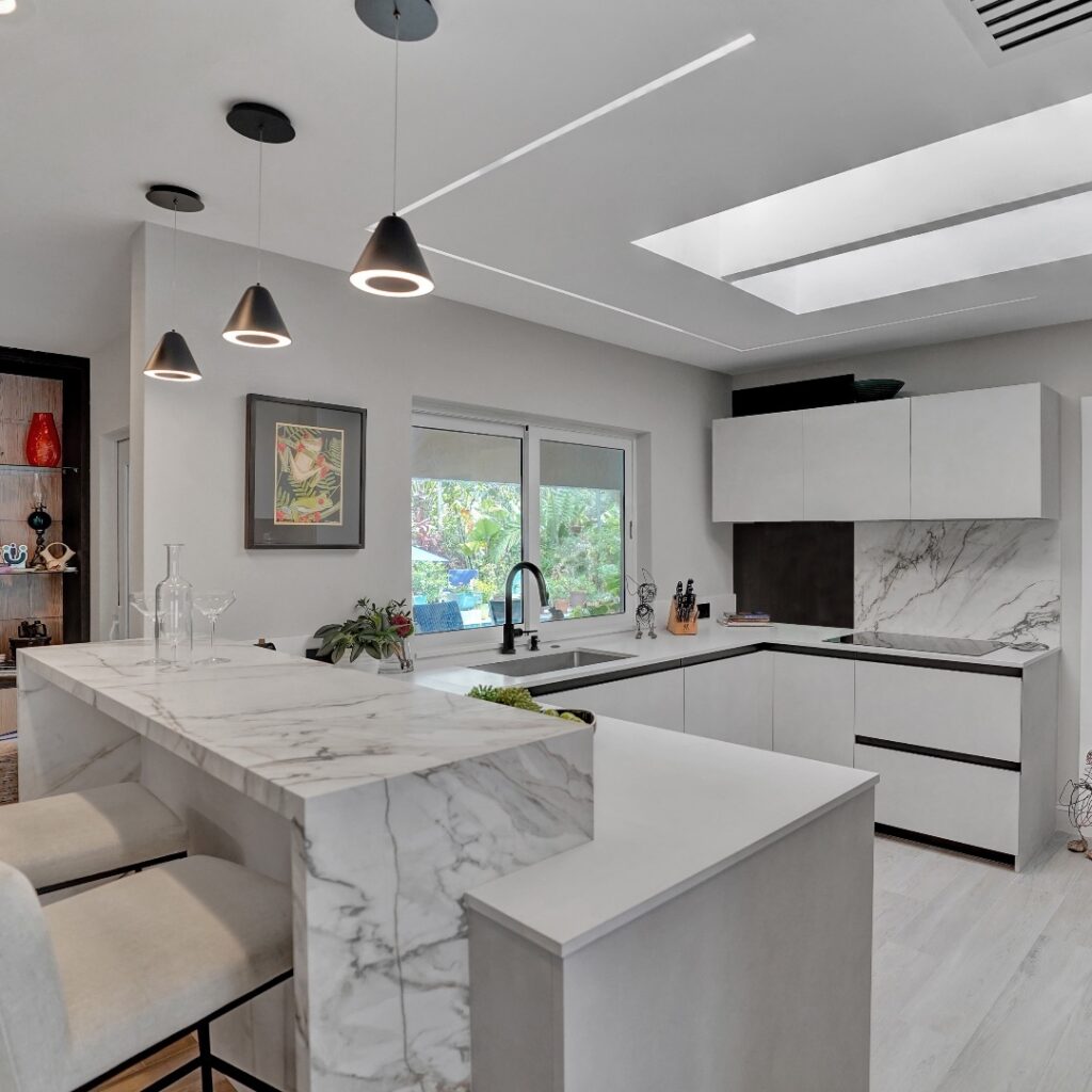 Modern white kitchen with marble countertops and pendant lights