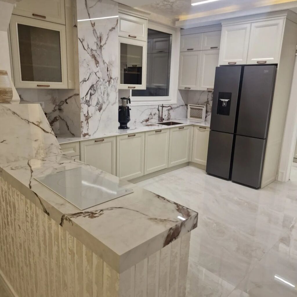 Beige kitchen with marble countertops and black refrigerator