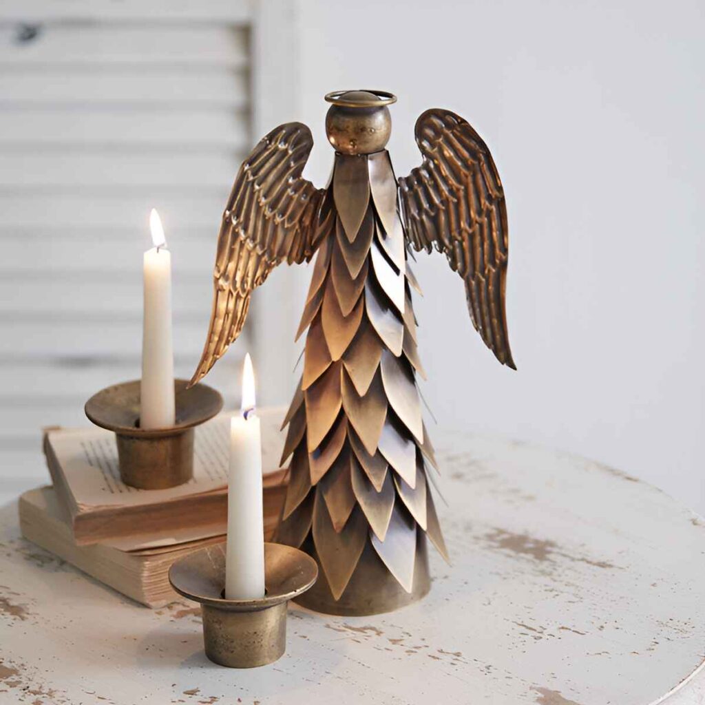 Metal angel sculpture with candles and books.