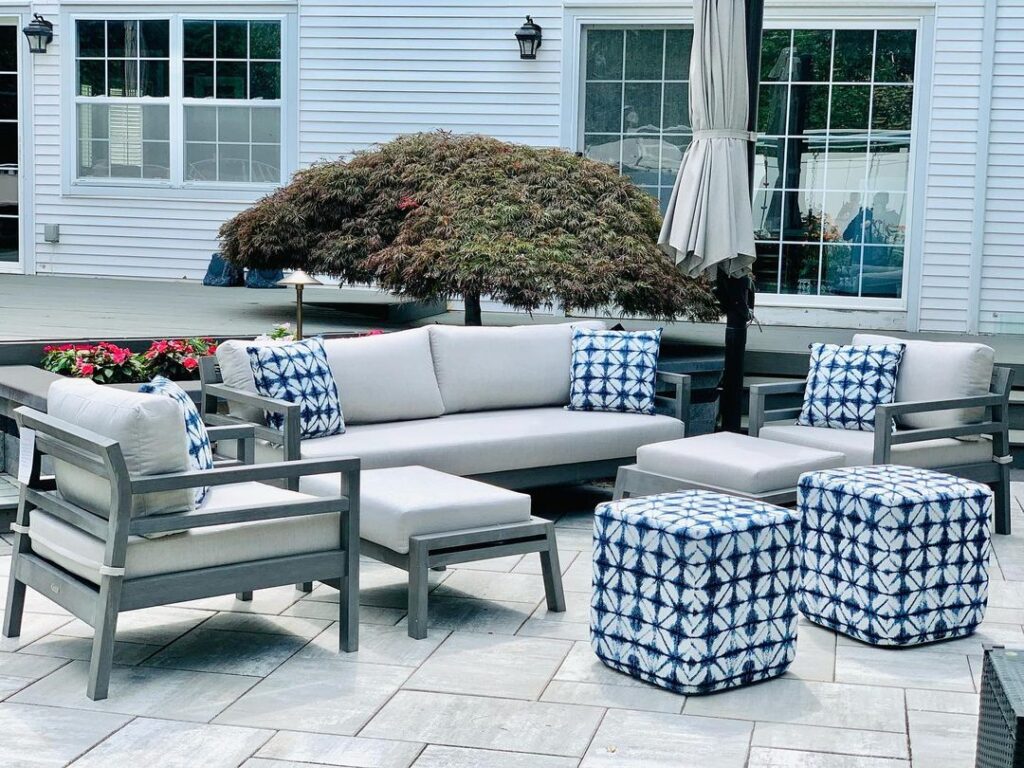 Modern patio furniture with blue and white accents under Japanese maple