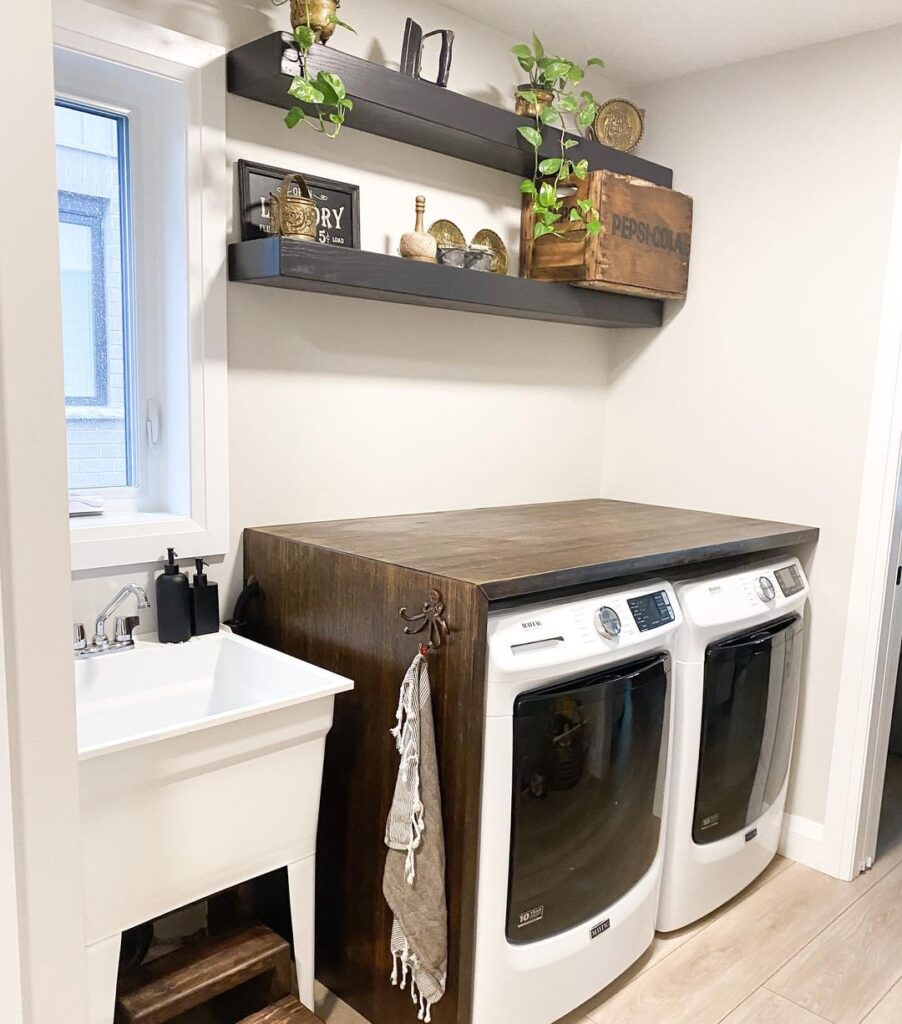 Laundry room with wooden countertop white appliances and dark shelves