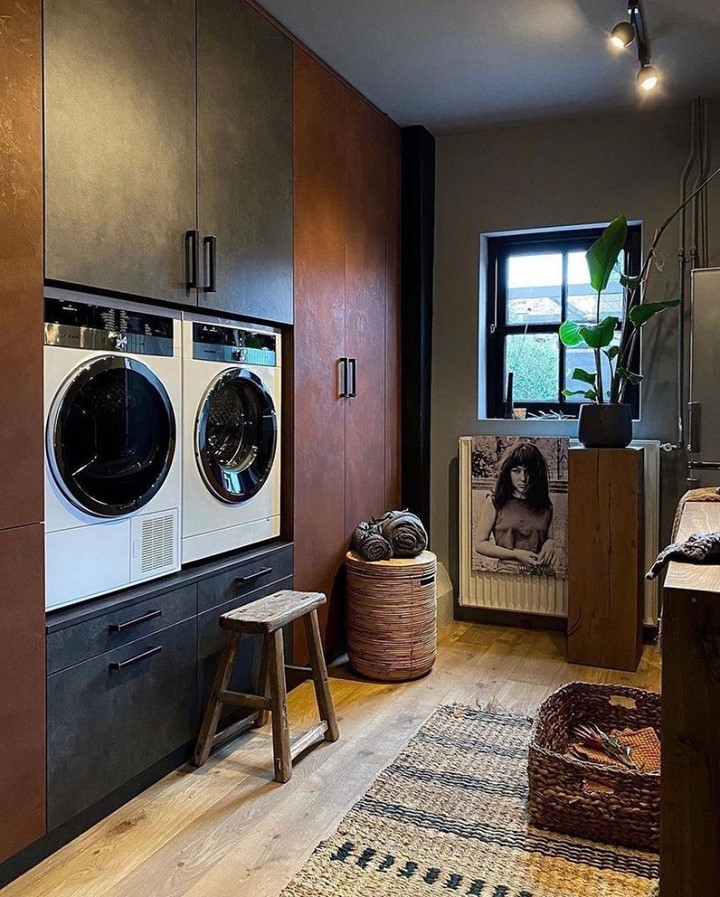 Dark laundry room with white appliances wooden accents and artistic decor.