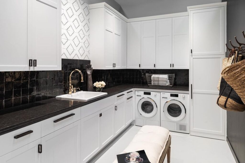 Upscale black and white laundry room with expansive storage and modern appliances.