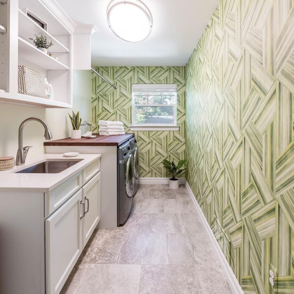 Laundry room with green geometric wallpaper and white cabinets