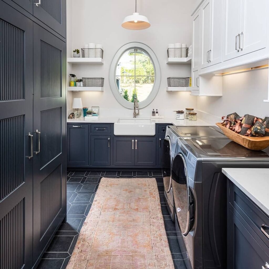 Stylish navy and white laundry room with round window and modern appliances.