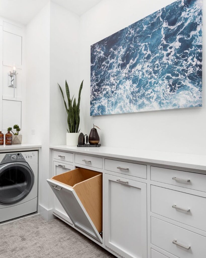 Laundry room with ocean artwork and built-in hamper.