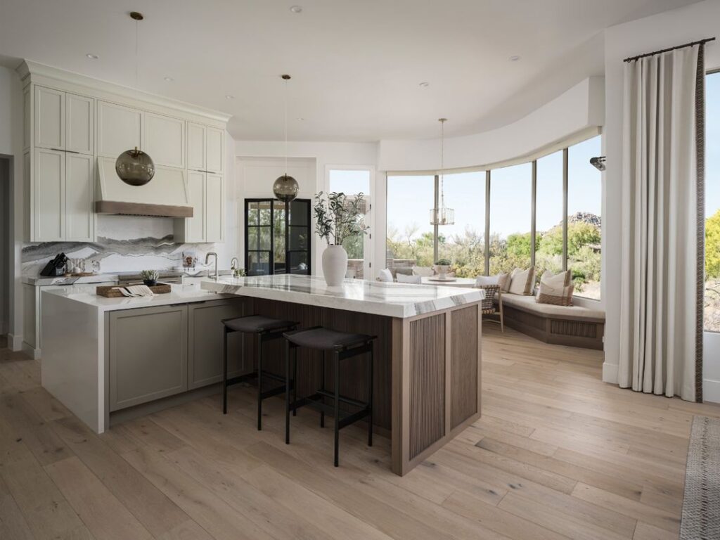 Open kitchen with curved windows overlooking greenery and desert landscape.