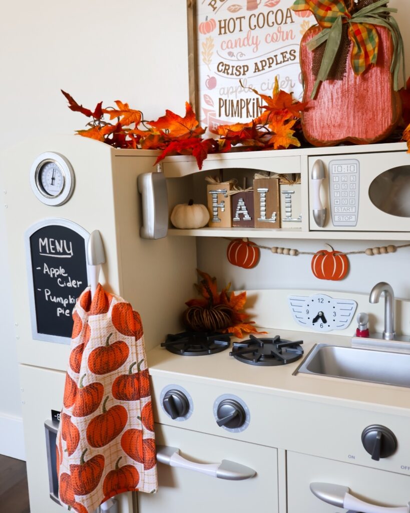 Child's play kitchen decorated with colorful fall-themed accessories