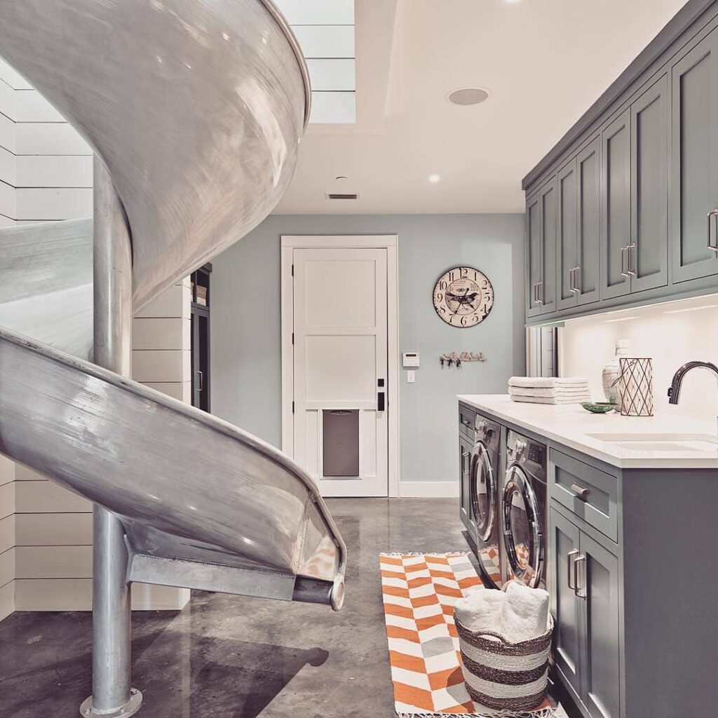 Laundry room with metal slide, gray cabinets, and vintage clock.