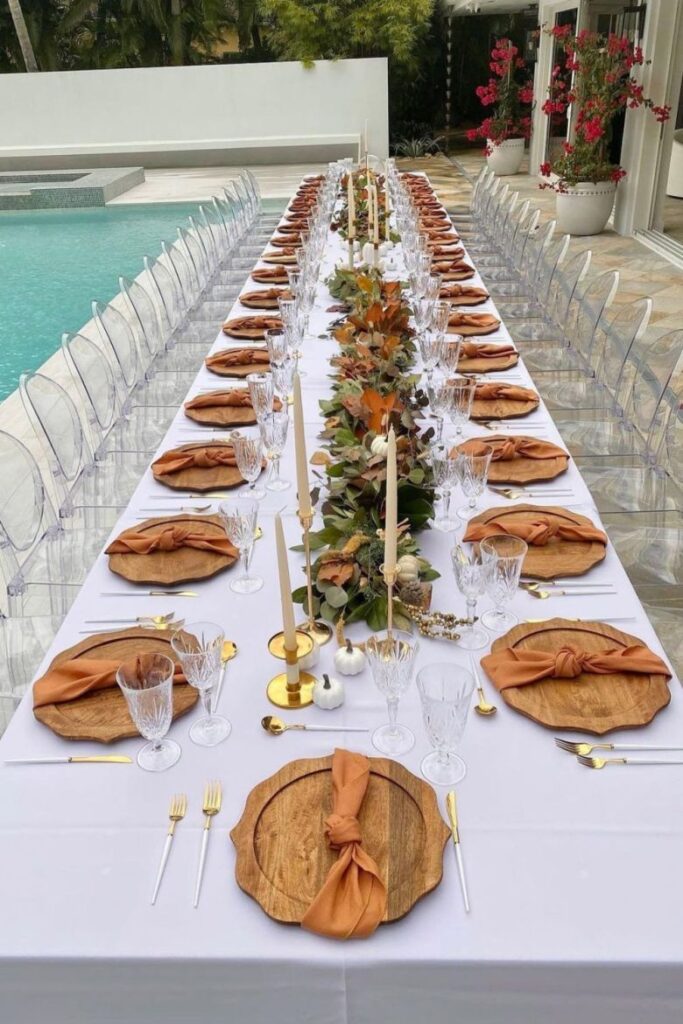 Outdoor Thanksgiving table by pool with wooden chargers and fall decor