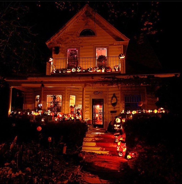 House illuminated by numerous glowing pumpkins