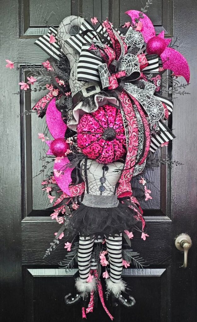 Halloween wreath with punk witch figure and pink accents.