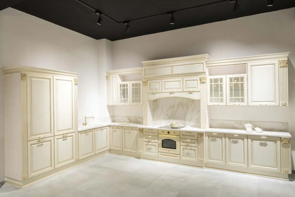 Beige L-shaped kitchen with gold trim and marble countertops.