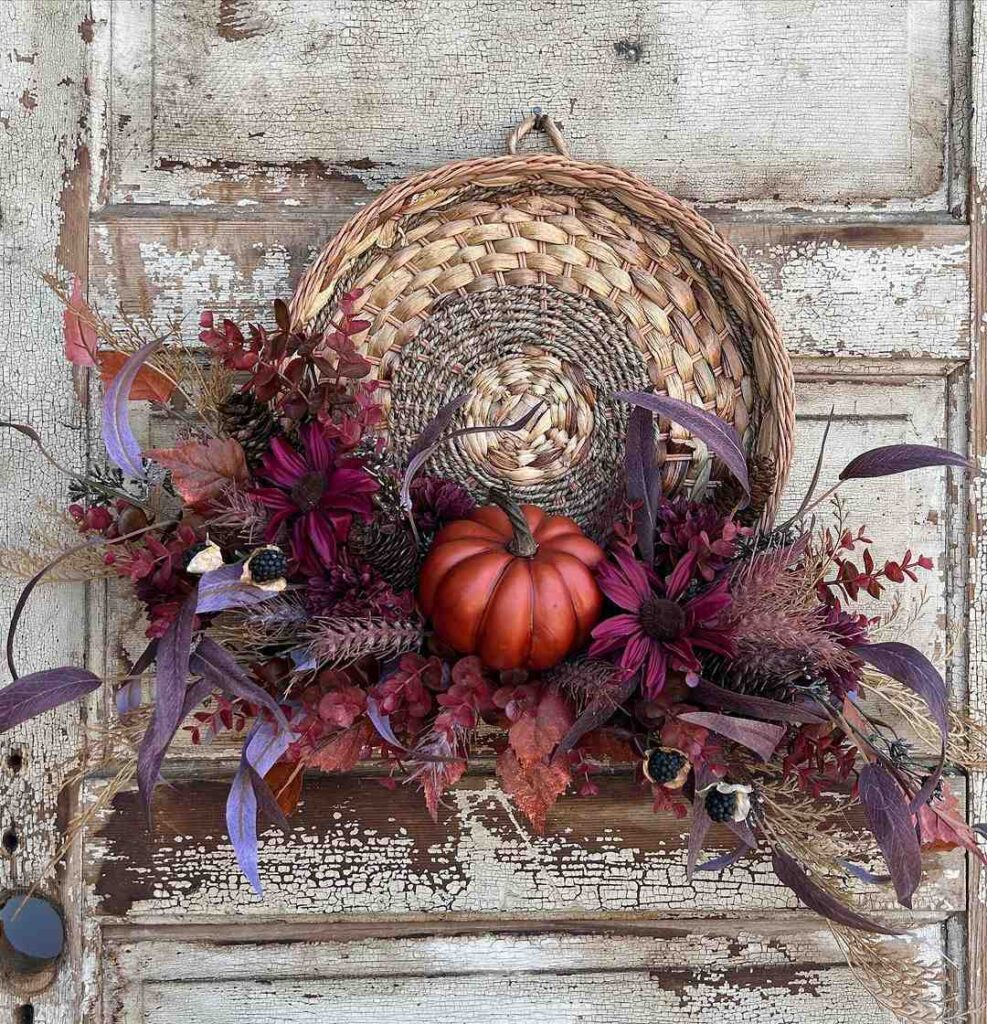 Woven basket with fall flowers pumpkin and foliage on rustic door