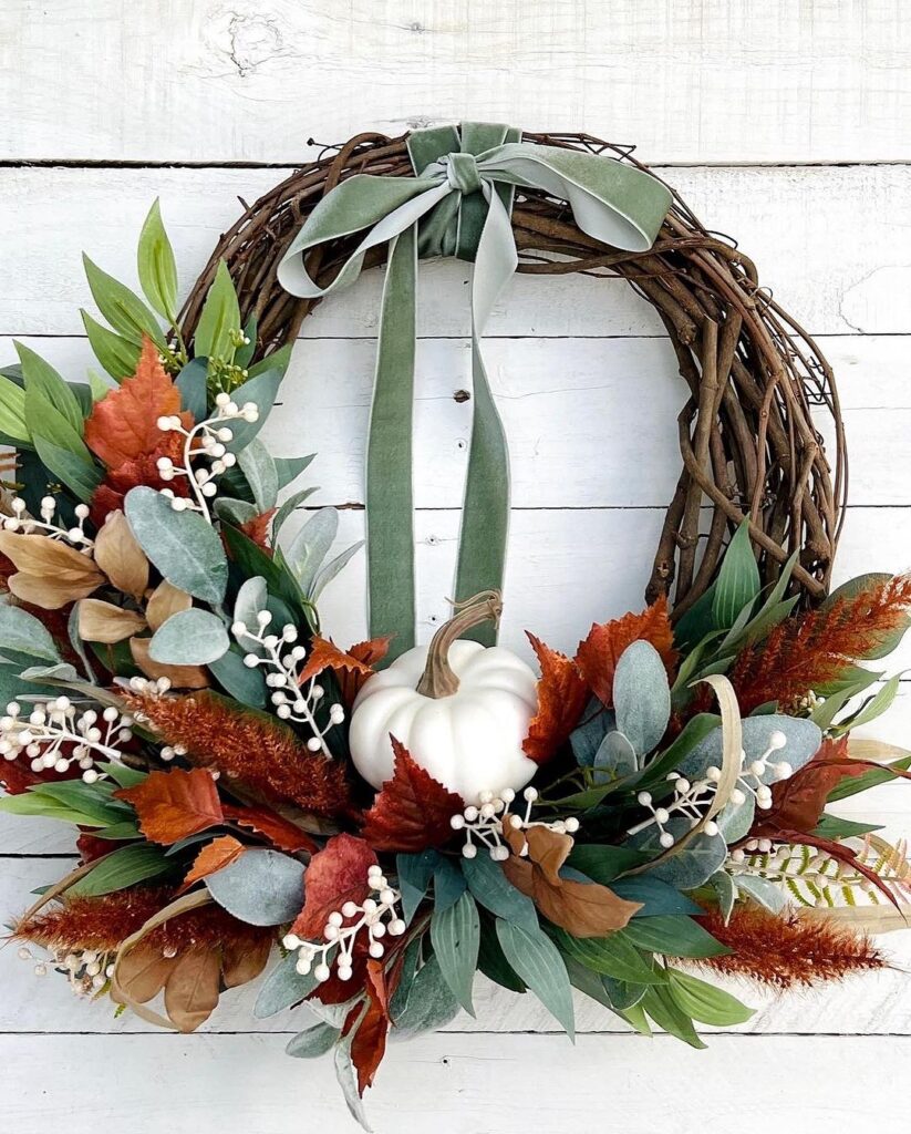 Grapevine wreath with white pumpkin autumn leaves and green bow.