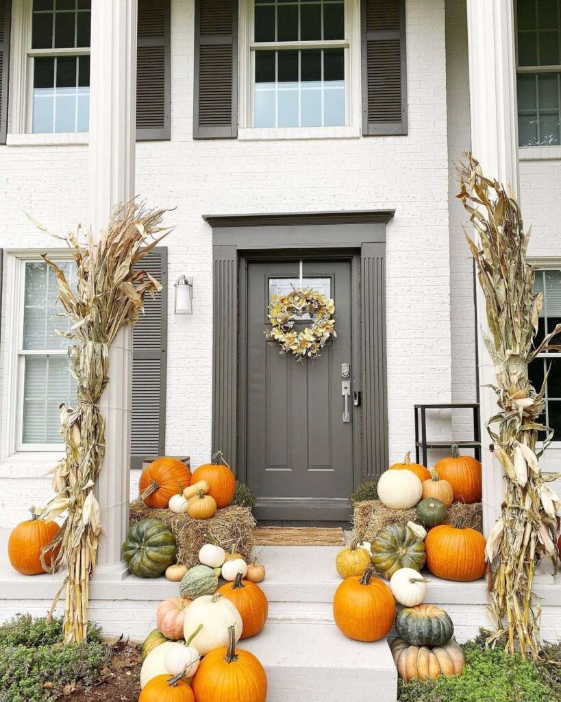 Farmhouse entrance decorated with fall pumpkins and cornstalks