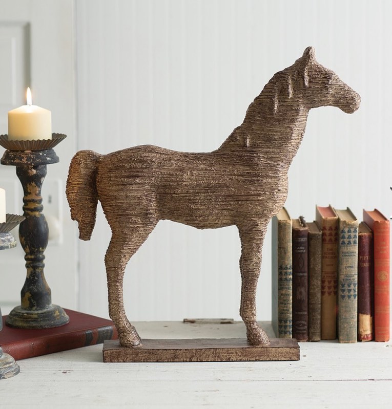 Wooden horse statue next to books and candle.