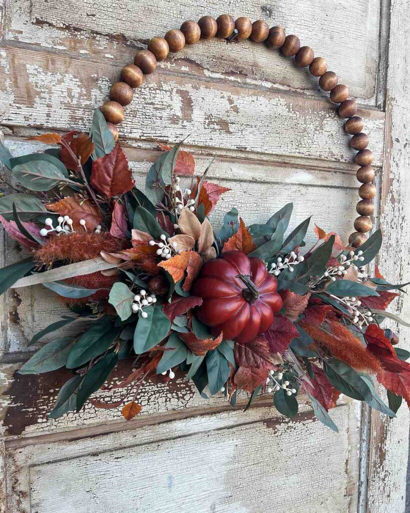 Wooden bead swag with fall leaves pumpkin and berries on rustic door