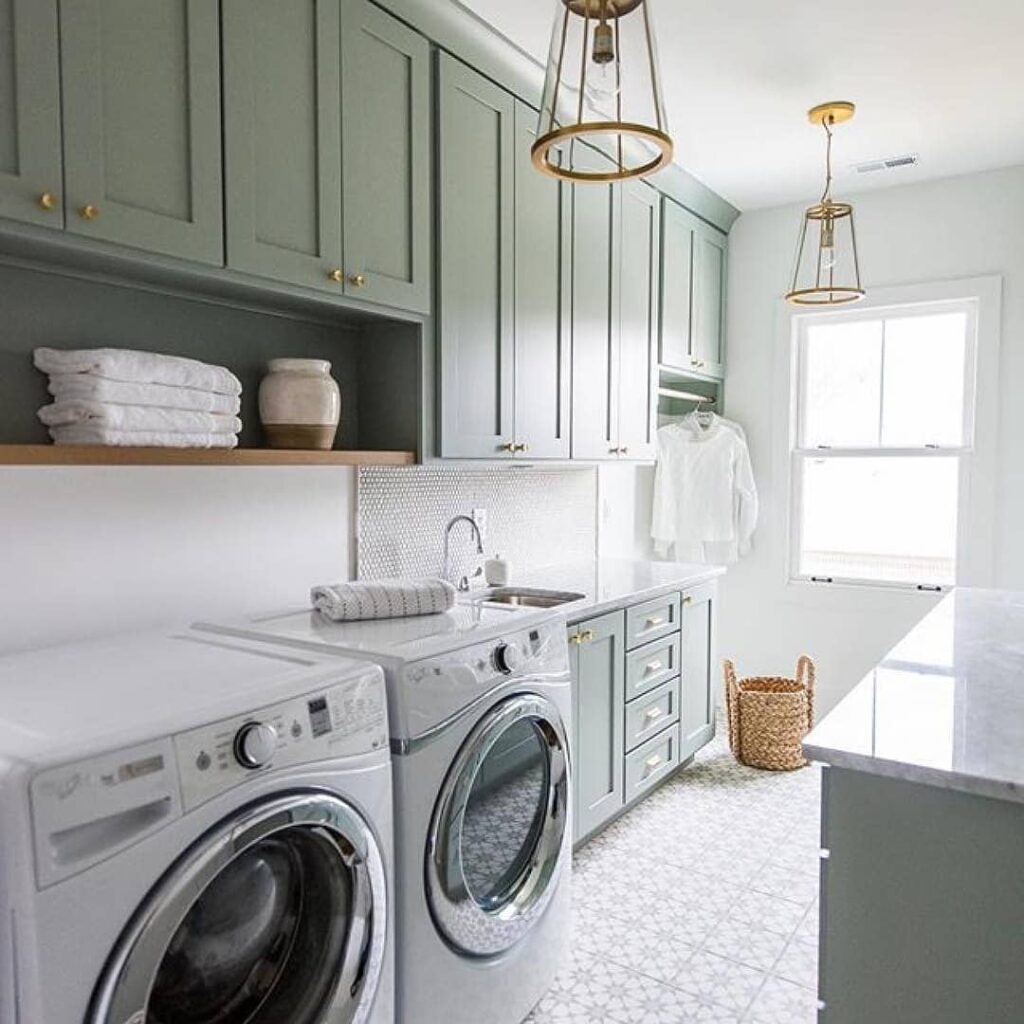 Elegant sage green laundry room with gold fixtures