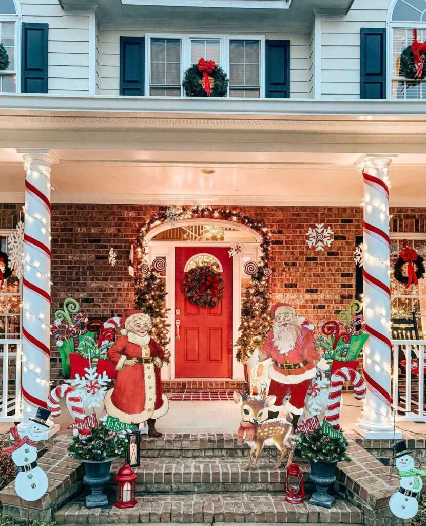 Brightly decorated Christmas porch with Santa Claus figures and red door