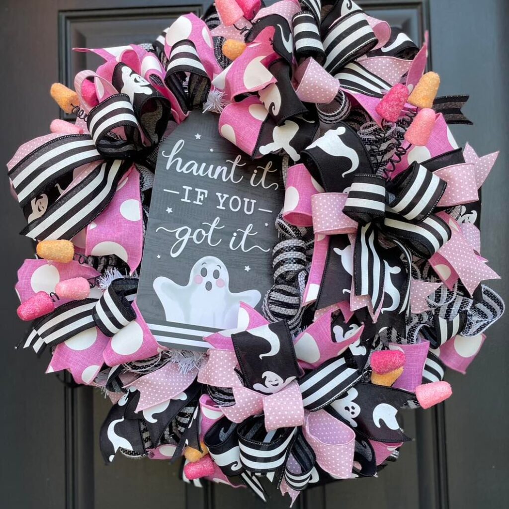 Pink and black ribbon wreath with ghost sign and candy accents.