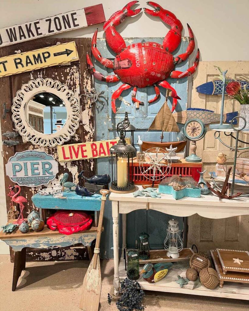 Coastal themed display with large red crab, weathered signs, and nautical decor items.