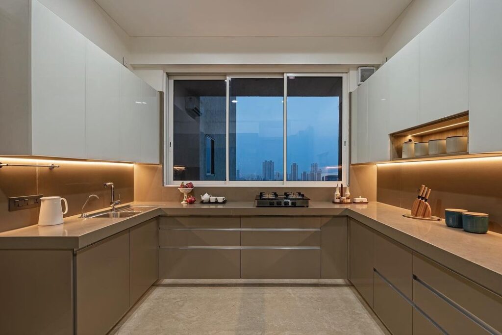 Modern beige kitchen with city view and ambient lighting.