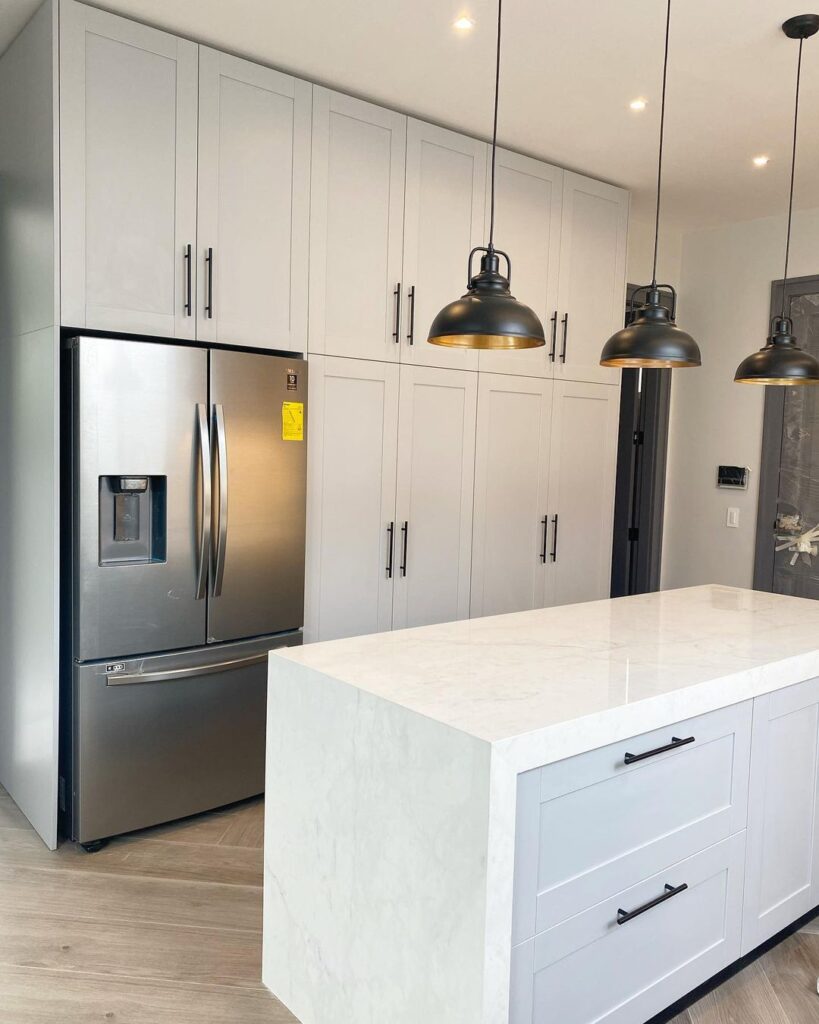 Modern white kitchen with black pendant lights and stainless fridge