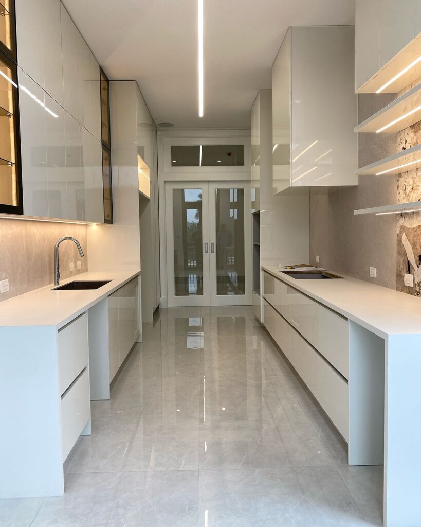 Modern white galley kitchen with LED lighting and glass doors