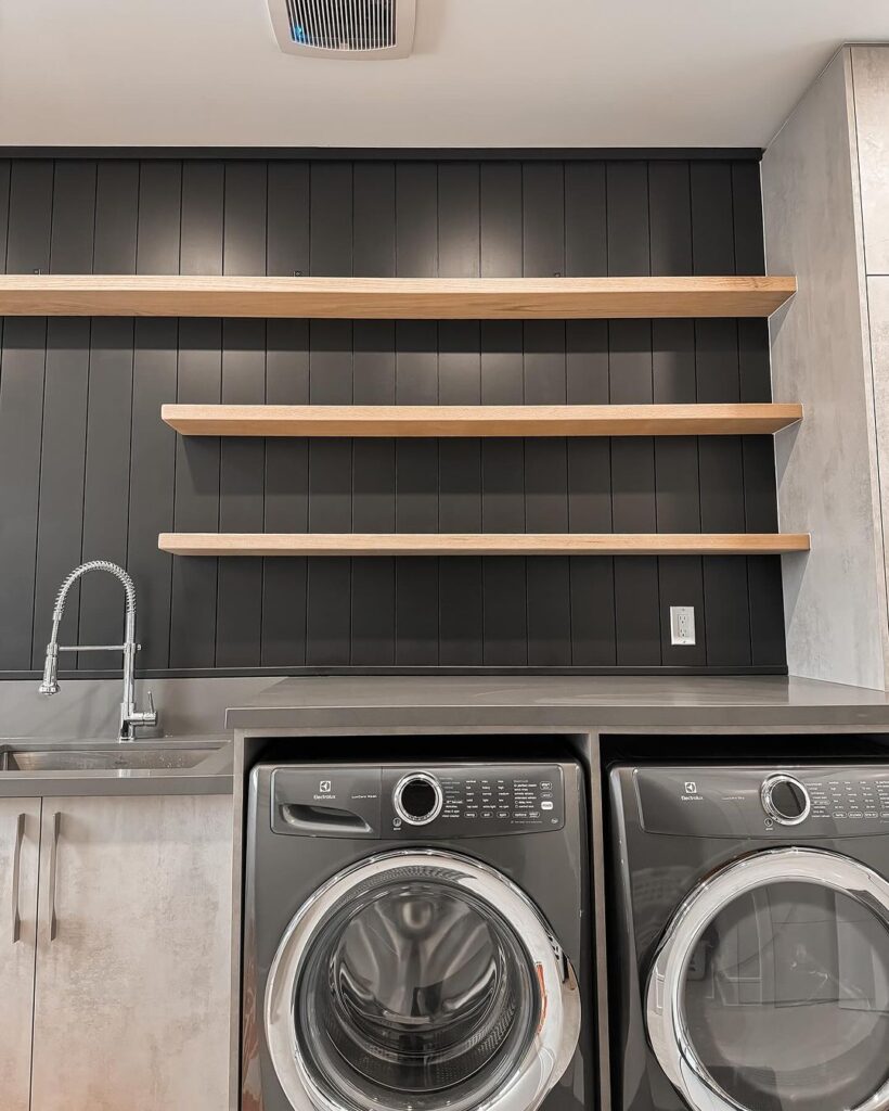 Contemporary laundry room with dark walls and floating shelves.