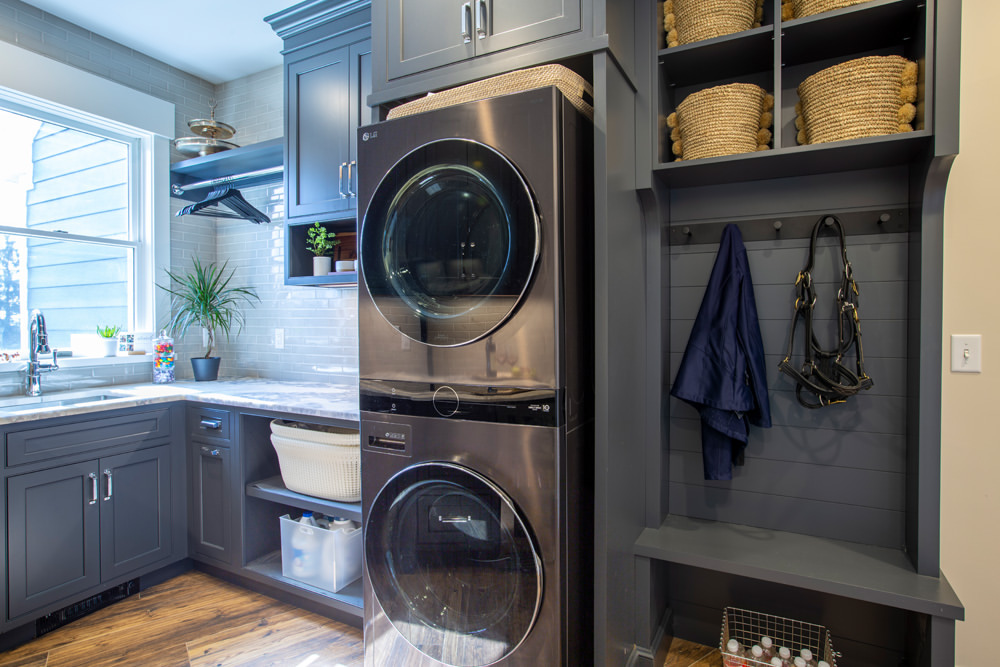 Stylish gray laundry room with stacked washer-dryer and mudroom area.