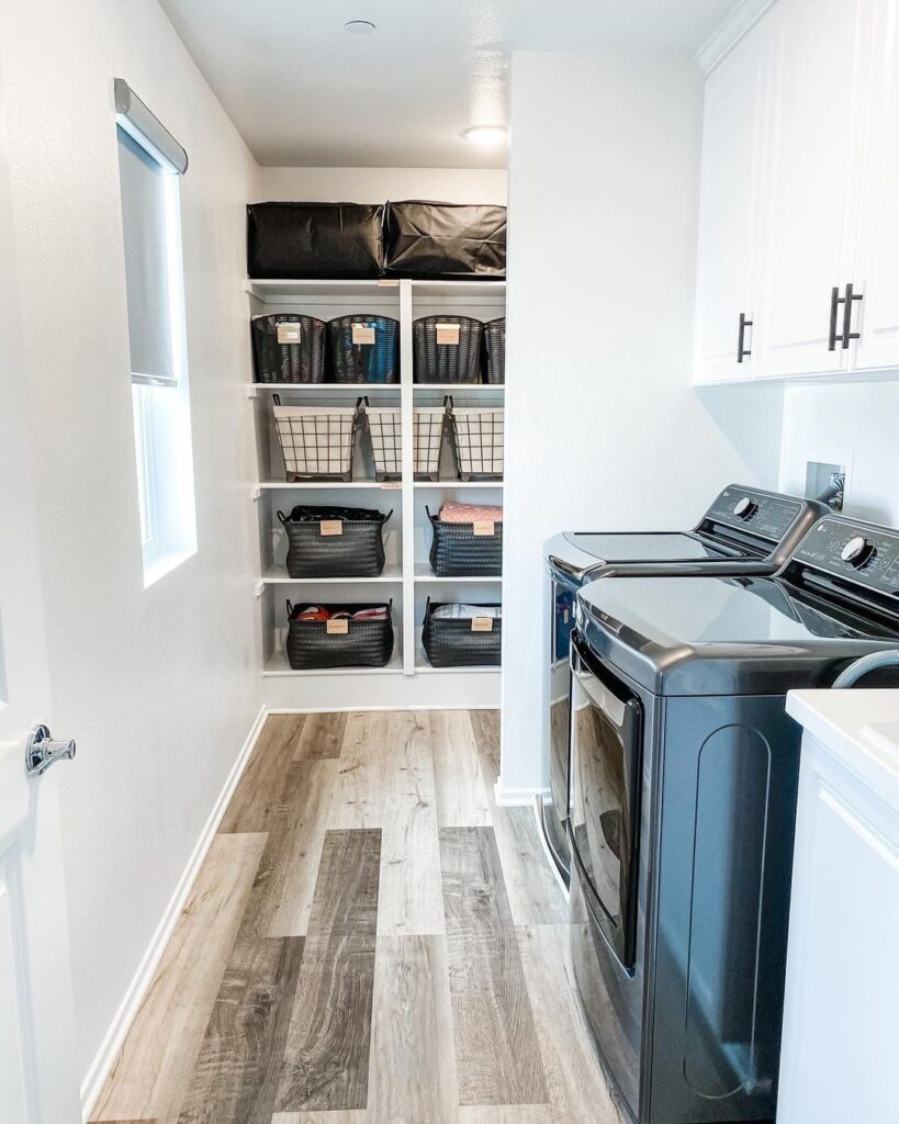 Organized laundry room with top-loading washer, built-in shelving, and various storage baskets.