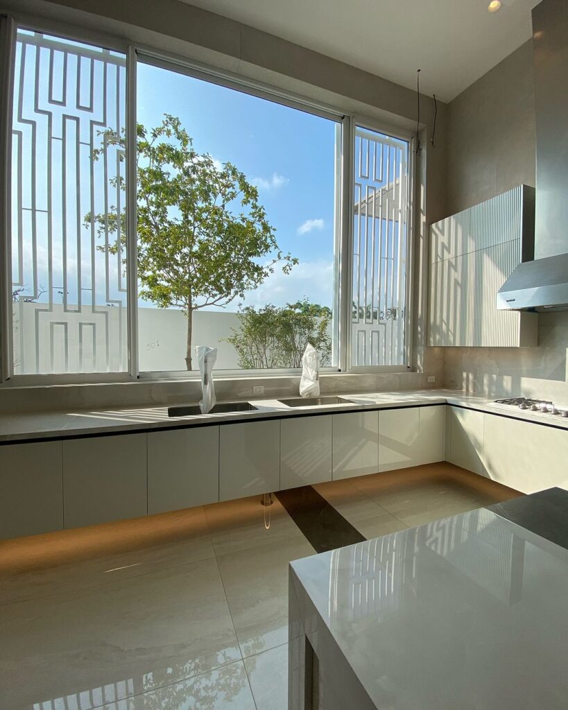 Modern white kitchen with large windows overlooking trees and sky