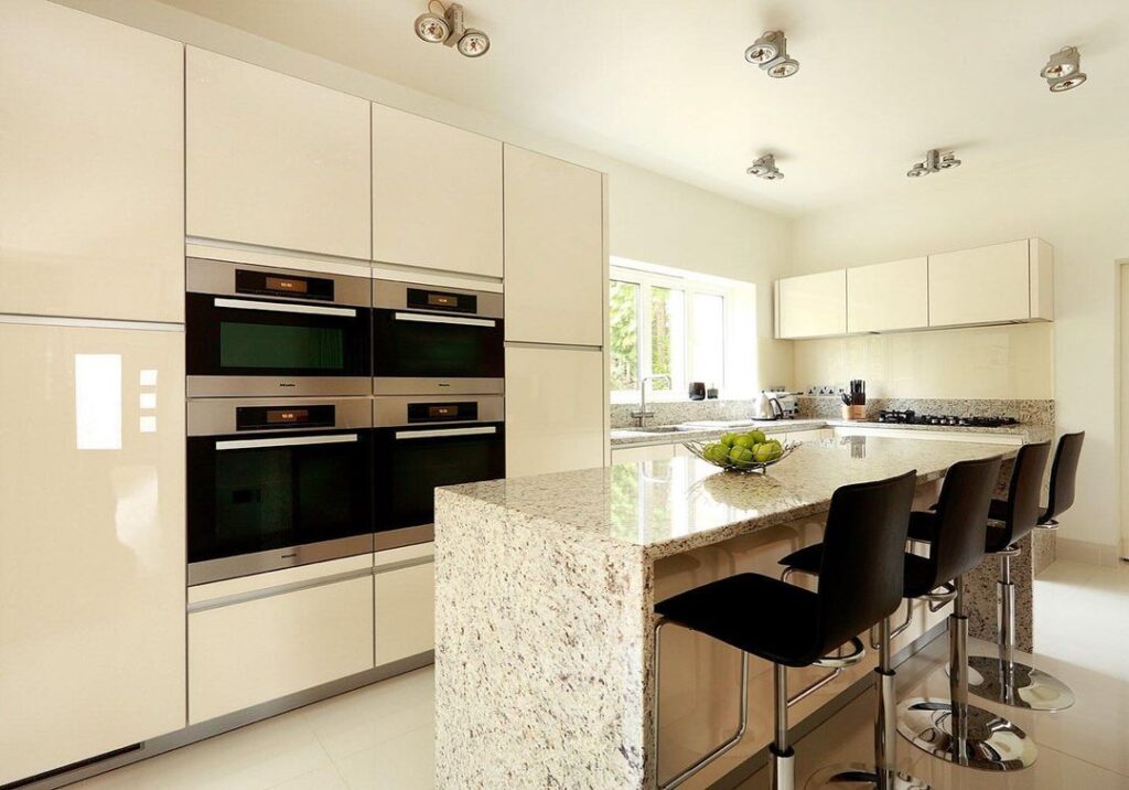 Bright modern beige kitchen with granite island and stainless appliances.