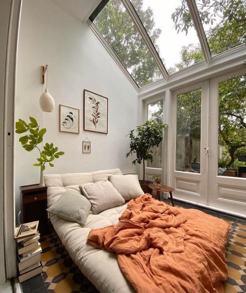 Bedroom with glass ceiling white walls orange bedding and garden view