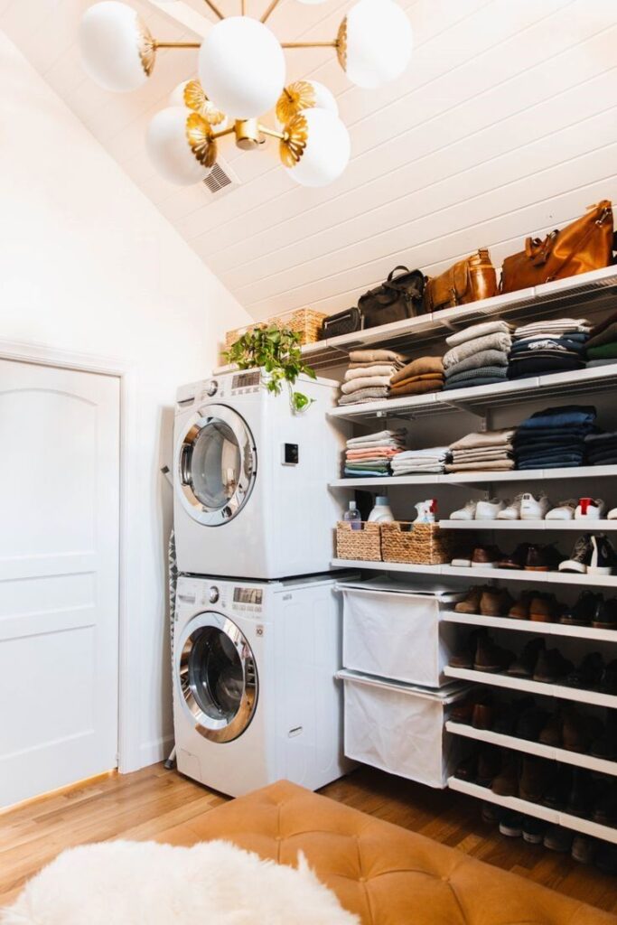 Bright laundry room with stylish lighting organized shelving and stacked appliances.