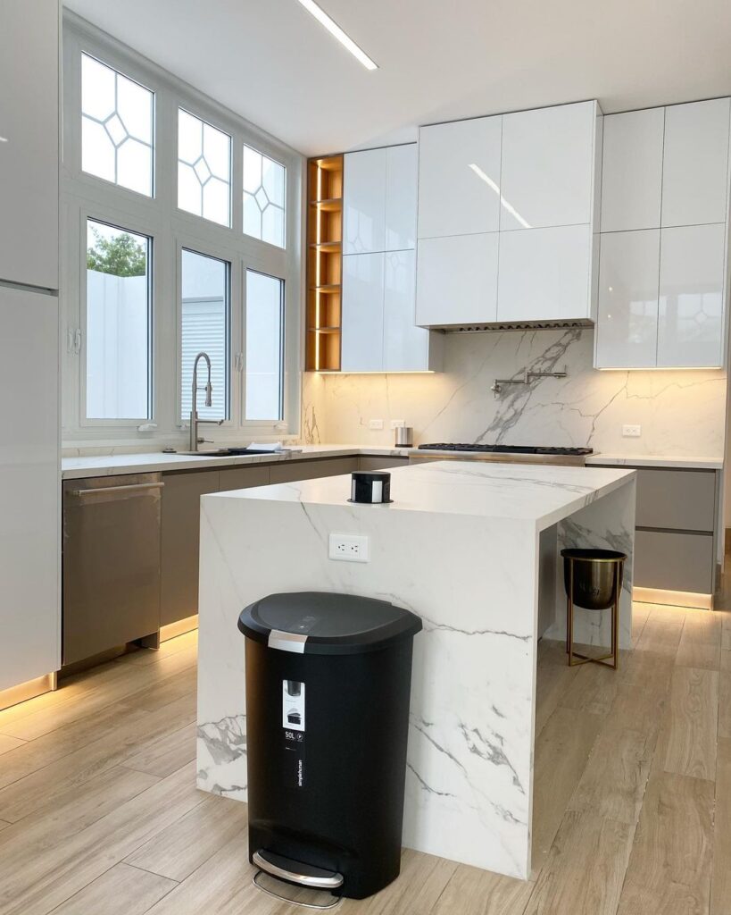 White kitchen with marble island and geometric windows.