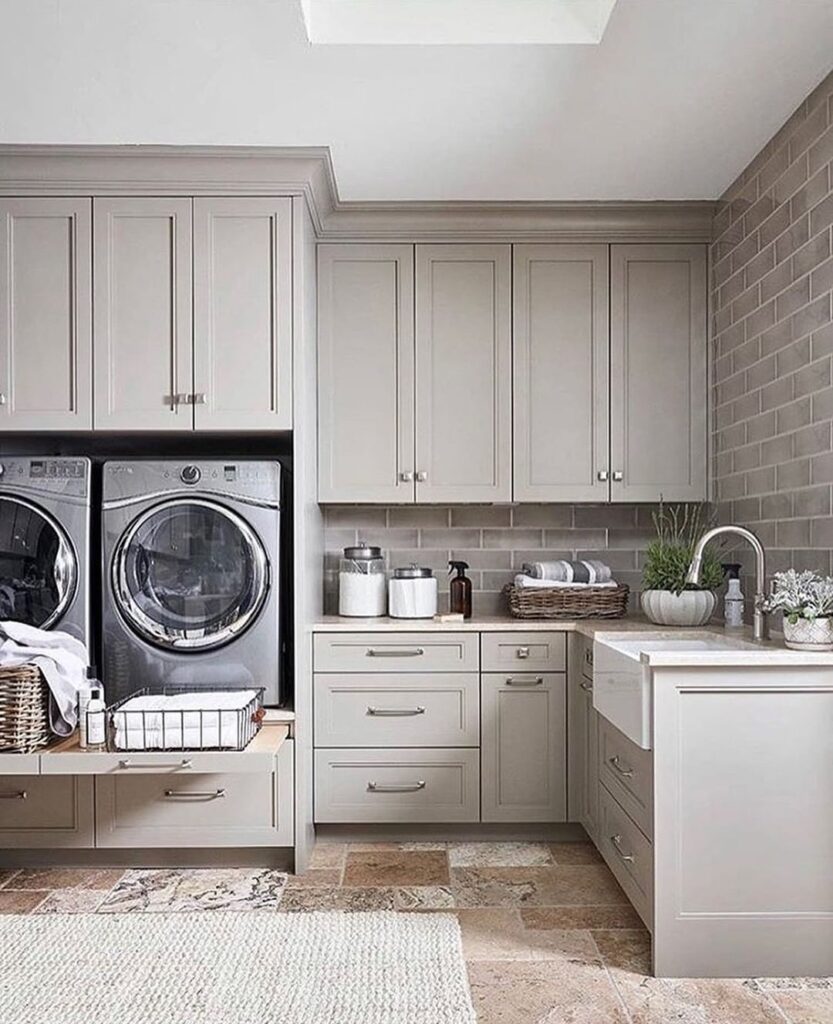 Spacious taupe laundry room with raised washer and dryer.