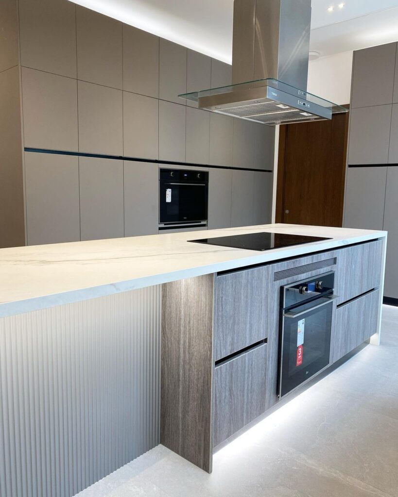 Modern kitchen with grey cabinets textured island and glass range hood