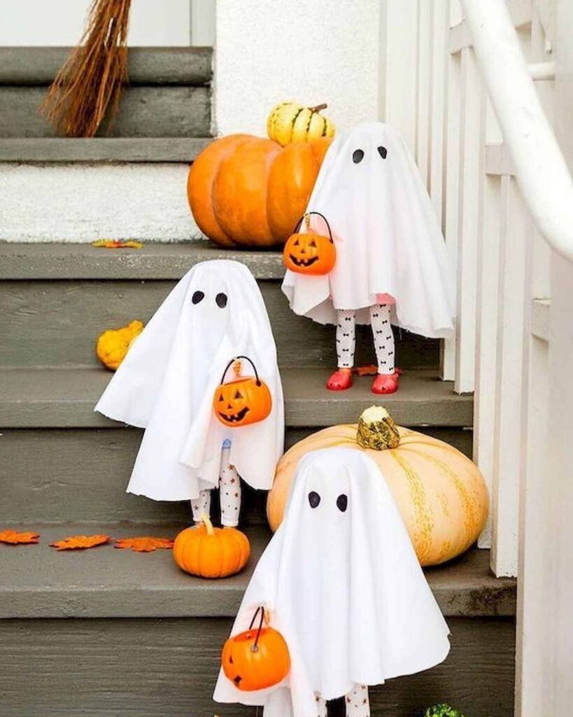 Cute ghost decorations and pumpkins on porch steps.