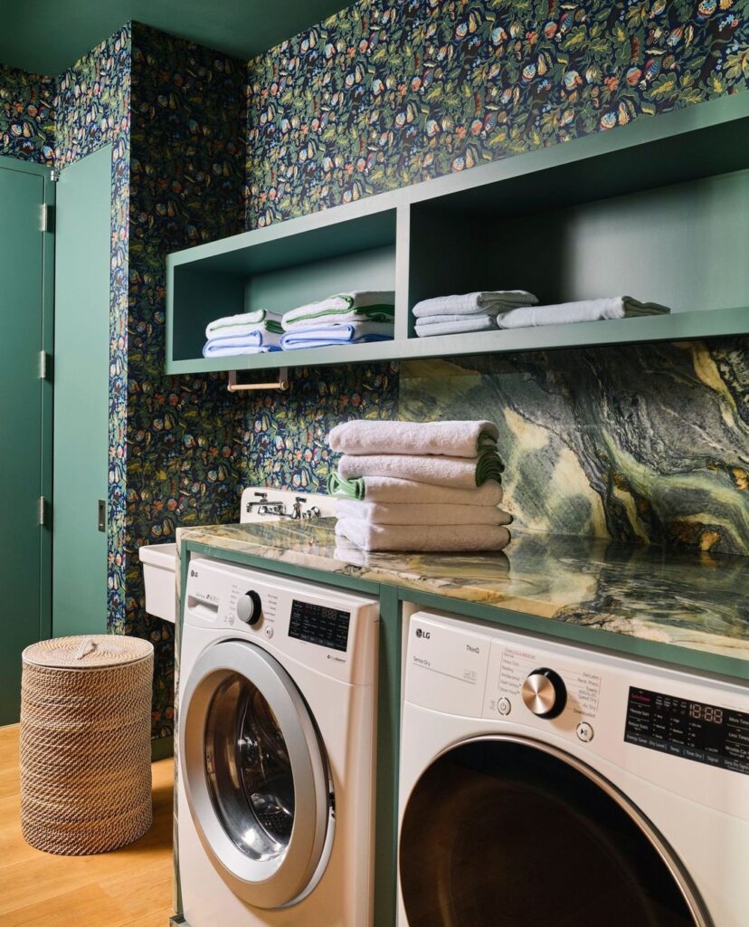 Laundry room with tropical wallpaper, green cabinets, and marble countertop.