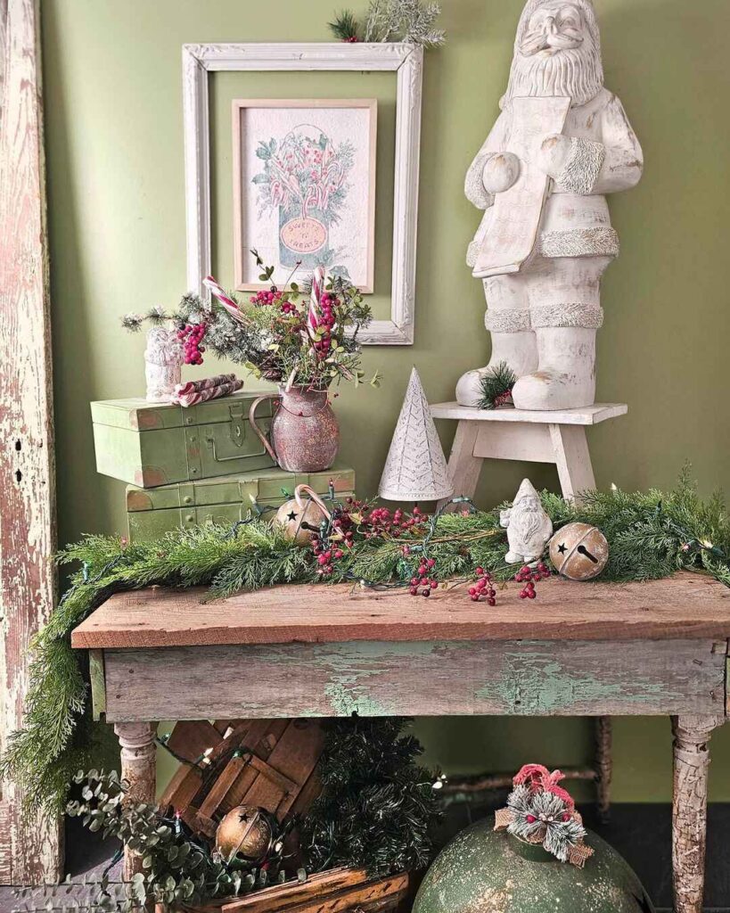 Vintage-style Christmas decor on rustic table with Santa statue.