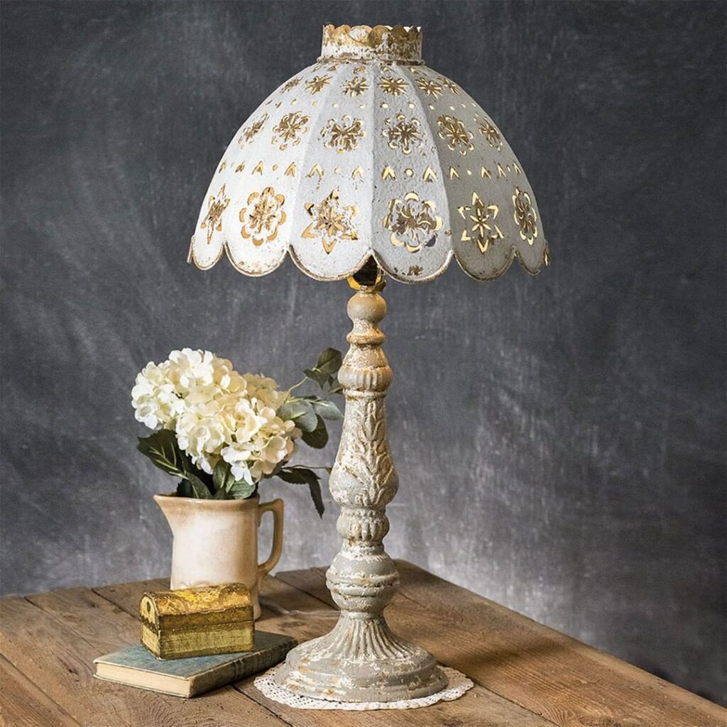 Antique lamp with lace shade beside flowers and books.